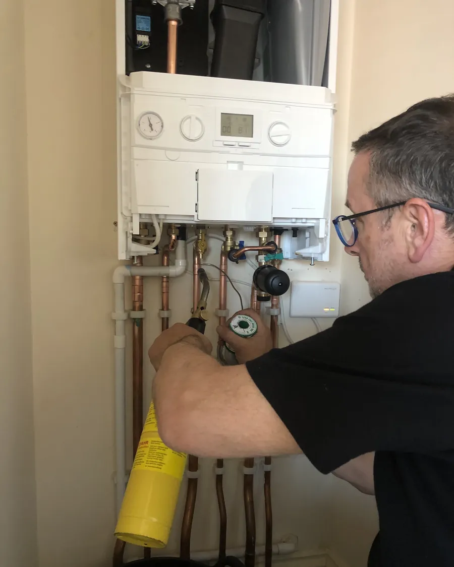 Vito working on the pipework beneath a combi boiler during a repair