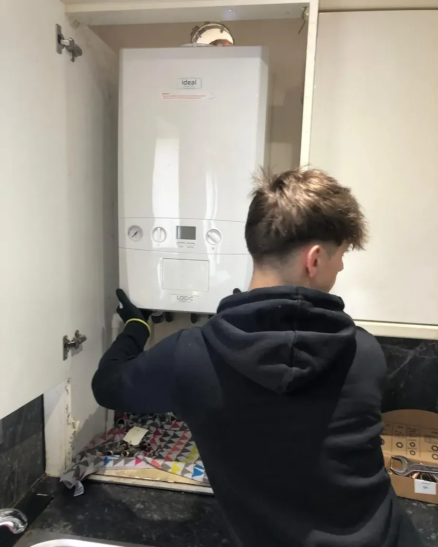Leo servicing an Ideal Logic combi boiler inside a kitchen cupboard