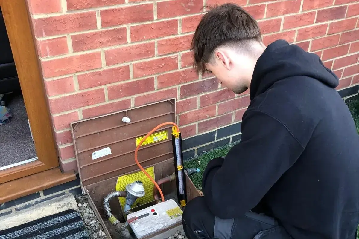 Engineer carrying out a gas tightness test at the outside gas meter of a rented property during a landlord gas safety inspection